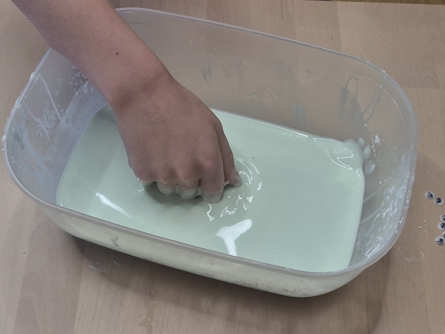 A fist pressed hard into pale green oobleck, held up by the firm surface instead of sinking in
