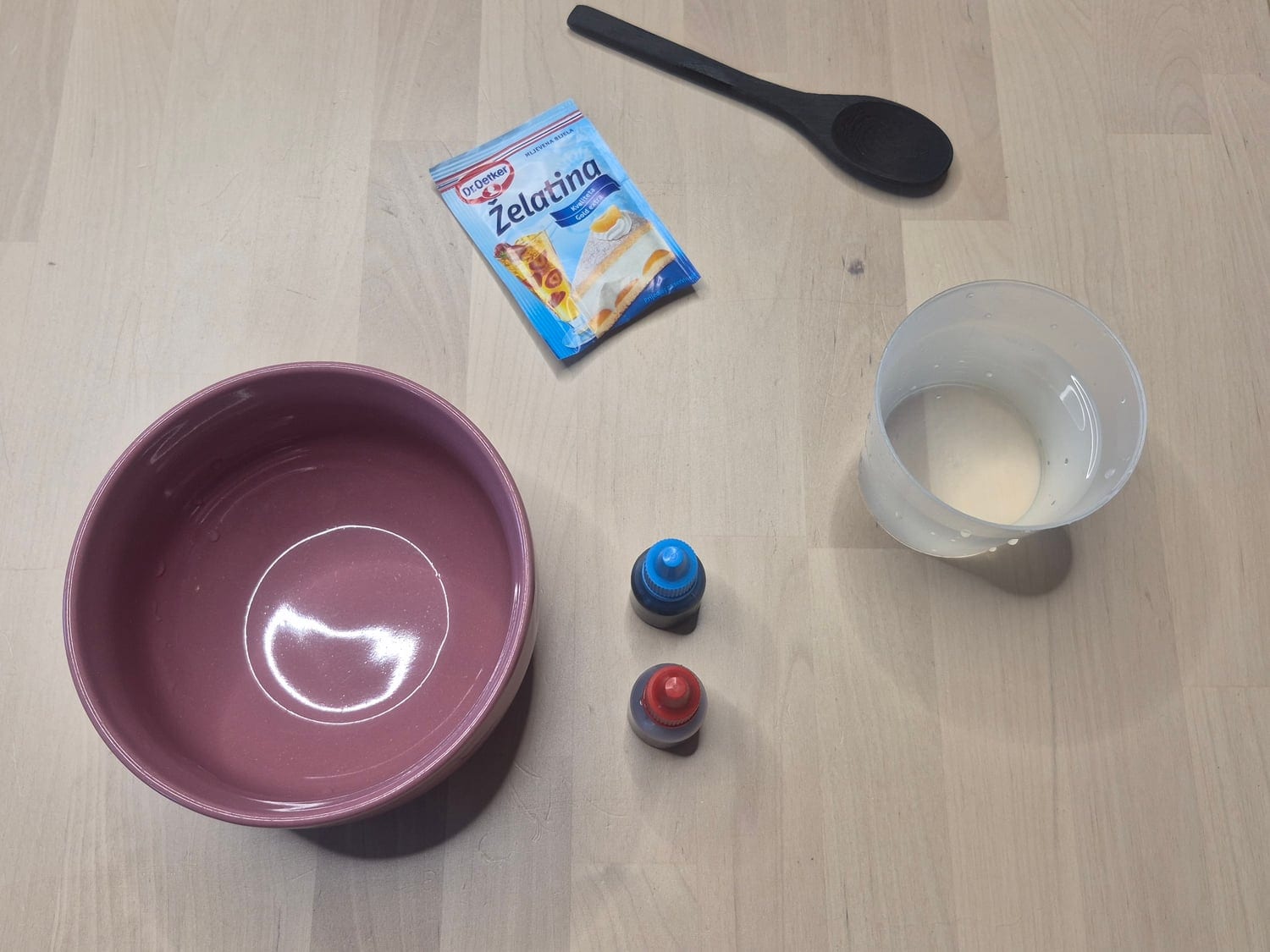 Bloody jelly goo materials: a sachet of gelatine, a pink bowl, a cup of hot water, red and blue food colouring and a spoon