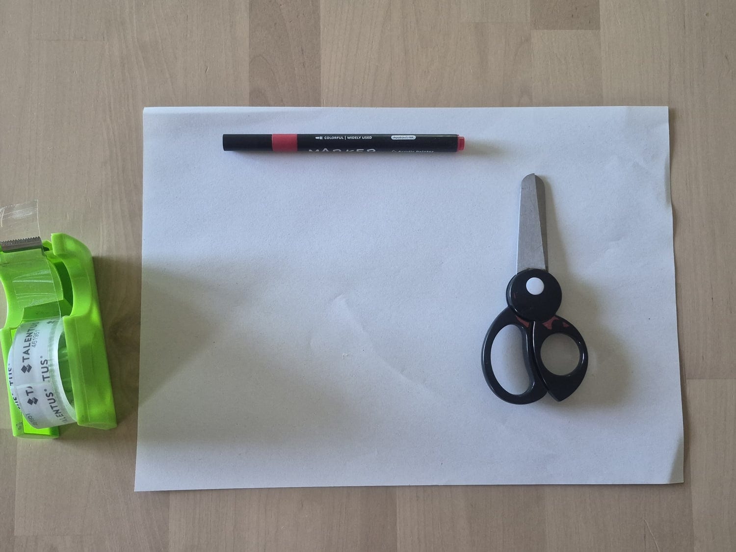 White paper with scissors, sticky tape and a red marker for making a Möbius strip