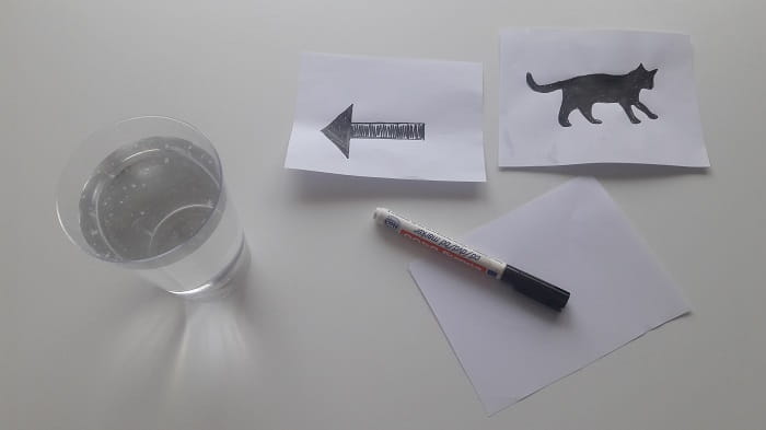 Čaša vode, olovka i papir s crtežima