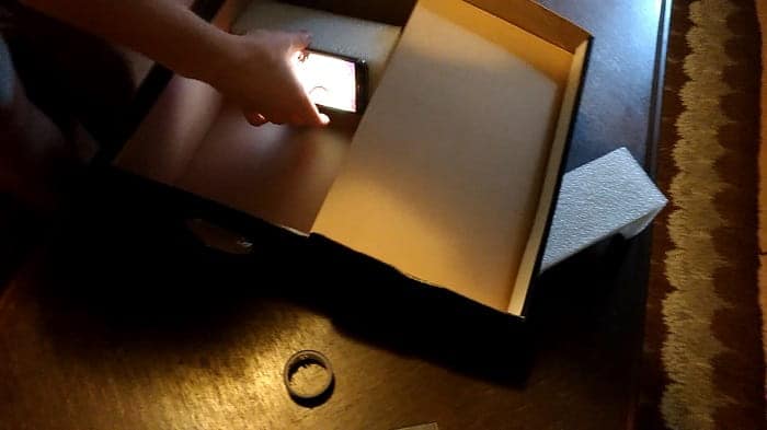 Smartphone mounted upside down on a homemade cardboard stand inside the box