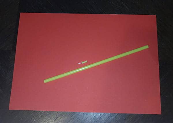 Materials for the paper windmill: colored paper, a pin, and a straw