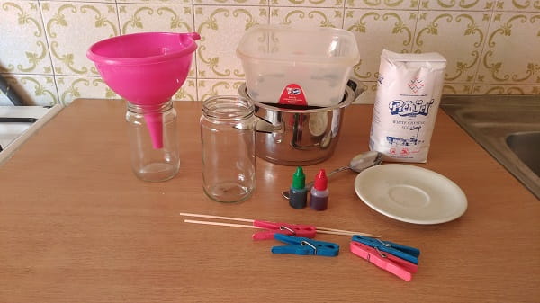 Šećer, voda, staklenke, lonac, drveni štapići i kvačice na stolu